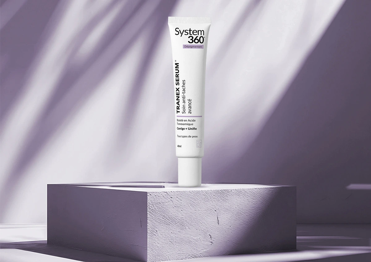 Soin Tranex Serum de System360 présenté sur un socle aux tons lilas, dans une lumière naturelle